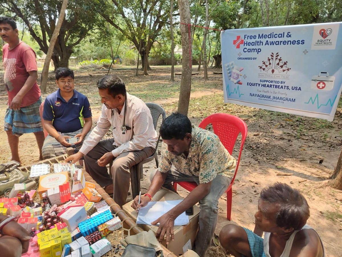 Doctor and volunteers at the free medical camp with medicines laid out, under the Equity Heartbeats banner