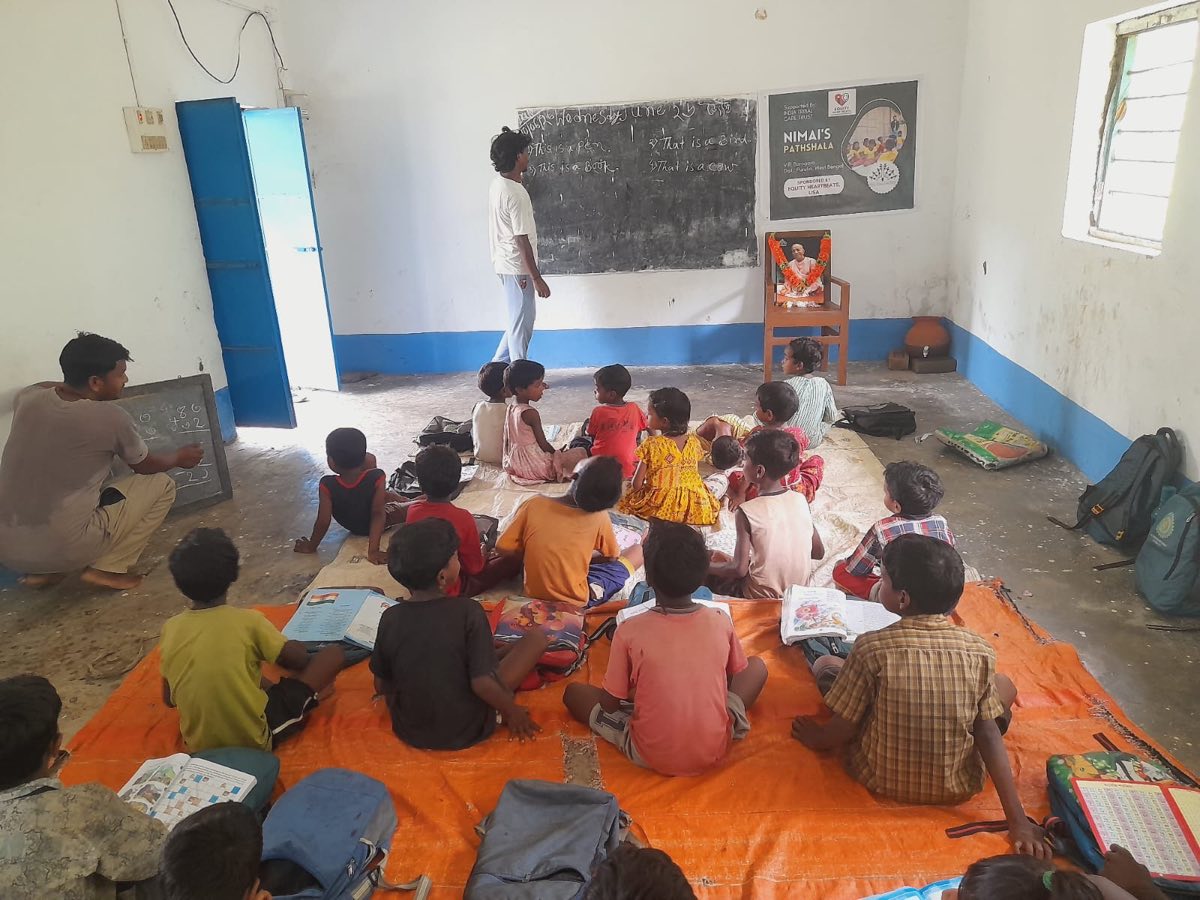 Children learning at Nimai's Pathshala with the Equity Heartbeats sponsorship poster on the wall